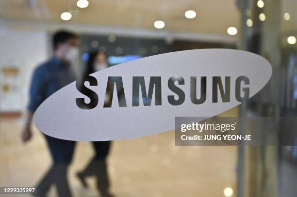 People walk past the Samsung logo at the company's showroom in Seoul on October 29, 2020.