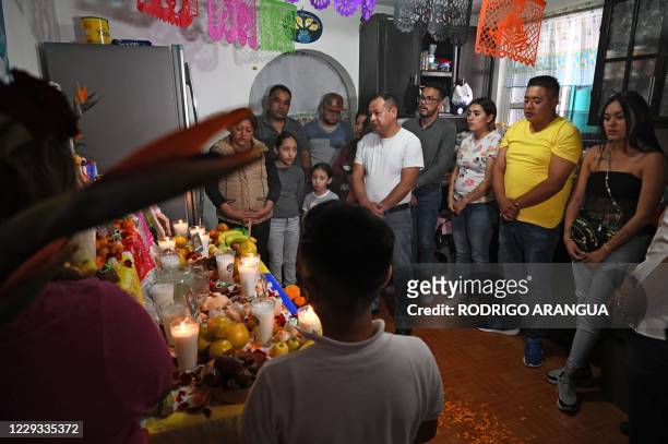 Relatives of Alma Delia Romero Sanchez, who died from Covid-19, pray next to an altar they prepared in her honor for the Day of the Dead, in Mexico...