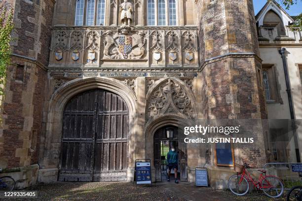 Man walks through the Great Gate at Trinity College, part of the University of Cambridge, in Cambridge, east England on October 14, 2020. - Going to...