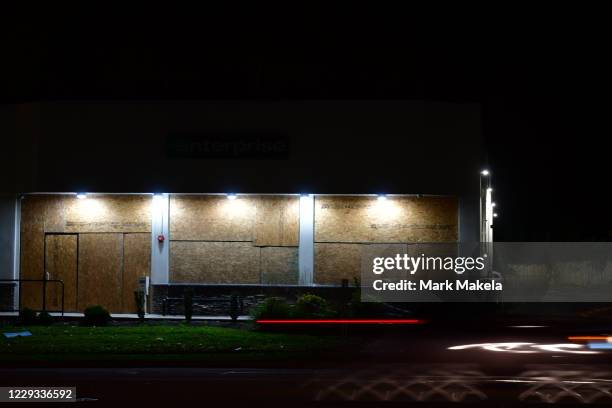 Car lights blur past a boarded up Enterprise Rental Agency to prevent looting during a citywide curfew on October 28, 2020 in Philadelphia,...