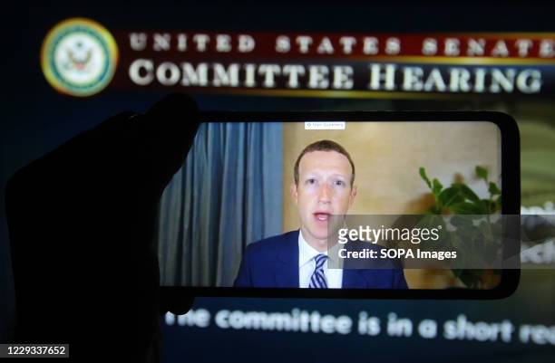 In this photo illustration, Facebook CEO Mark Zuckerberg seen on a mobile screen as he remotely testifies during the hearing of U.S. Senate Committee...