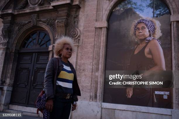 Julie Meyrand poses on October 28,2020 next to her portrait taken by photographer Antony Micallef, during the inauguration of the outdoor exhibition...