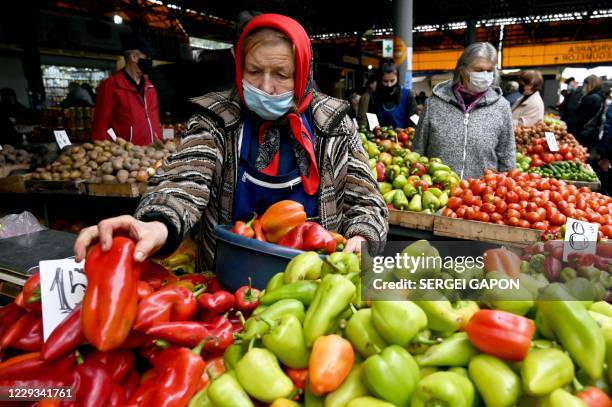 Woman wearing a face mask to protect against the coronavirus disease sells seasonal vegetables at the Central Market in Chisinau on October 29, 2020.