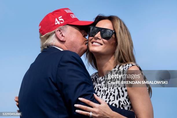 President Donald Trump kisses US First Lady Melania Trump during a "Make America Great Again" rally at Raymond James Stadium's parking lot on October...