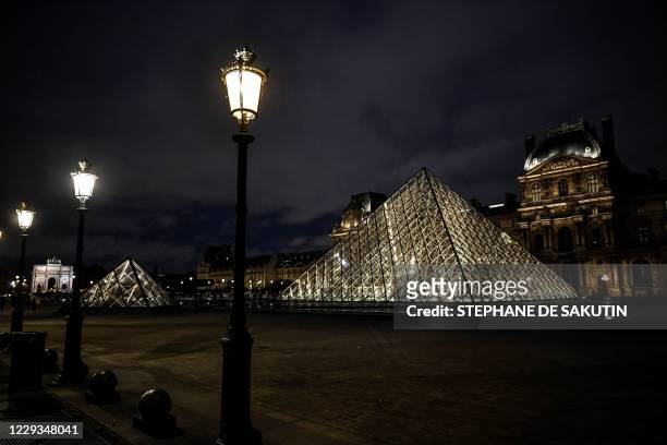 This photograph taken on October 29, 2020 in Paris shows an exterior view of the Musee du Louvre at its closing time and the Pyramide du Louvre,...