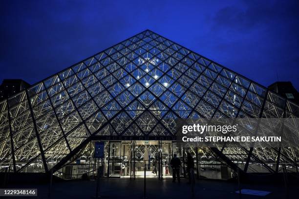 This photograph taken on October 29, 2020 in Paris shows an exterior view of the Musee du Louvre at its closing time and the Pyramide du Louvre,...