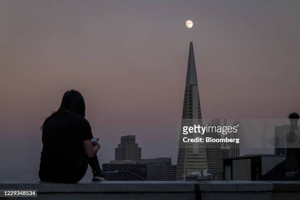 Person uses a smartphone as the moon rises over the Transamerica Pyramid building in San Francisco, California, U.S., on Wednesday, Oct. 28, 2020. A...