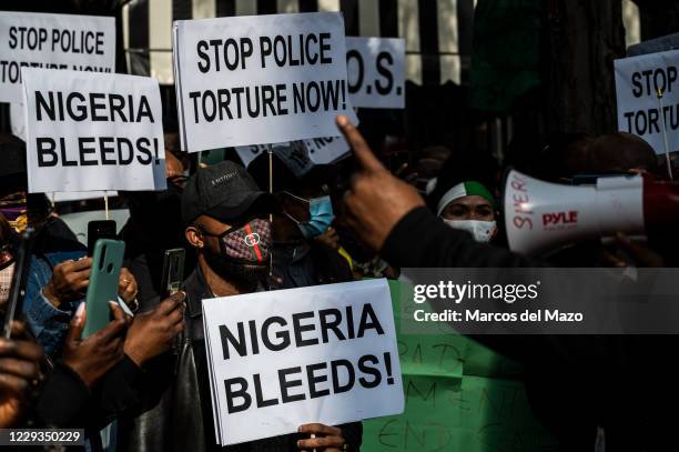 People hold placards during a protest where Nigerian community in Madrid demonstrate demanding the end of SARS , the end of police brutality and the...