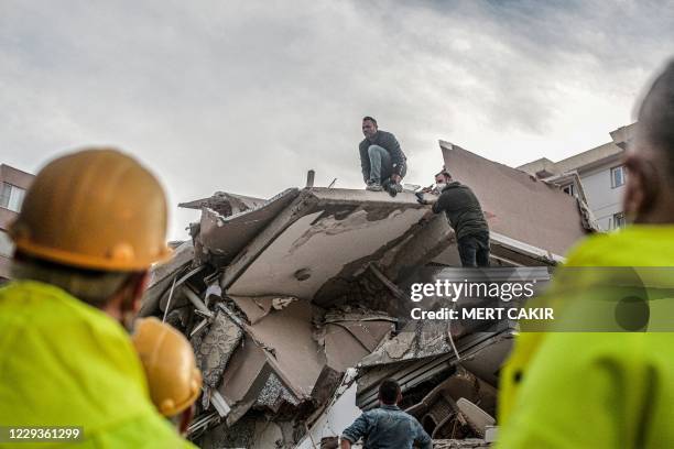 Volunteers clear rubbles as they search for survivors in a collapsed building after a strong earthquake struck the country's western coast and parts...