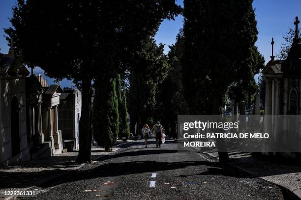 Couple wearing face masks walk at the Alto de Sao Joao cemetery in Lisbon on October 30, 2020 on the eve of All Saints' Day amid the coronavirus...