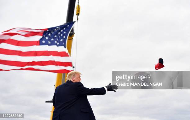 President Donald Trump tosses hats before speaking at a "Make America Great Again" rally at Oakland County International Airport, on October 30 in...