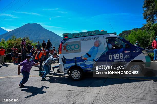 Group of men push an ambulance during the stage 8 of the Vuelta a Guatemala cycling race in San Pablo La Laguna, 165 km west of Guatemala City, on...