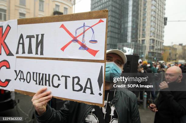Protester wearing a face mask holds a placard during the demonstration outside the Constitutional Court in Kiev. On October 27, the Constitutional...