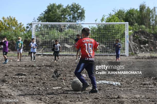 Children play football on a dirt field called after Catholic priest Bachi, inaugurated during a charity event on the 60th birthday of Argentine...