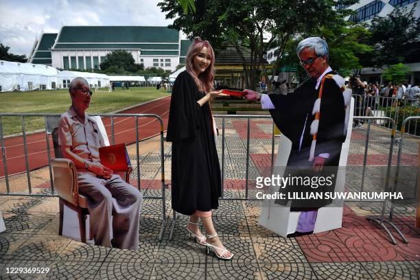 Graduating student poses for a selfie receiving a mock diploma from a cardboard cutout of Somsak Jeamteerasakul, a Thai academic in exile, during a...