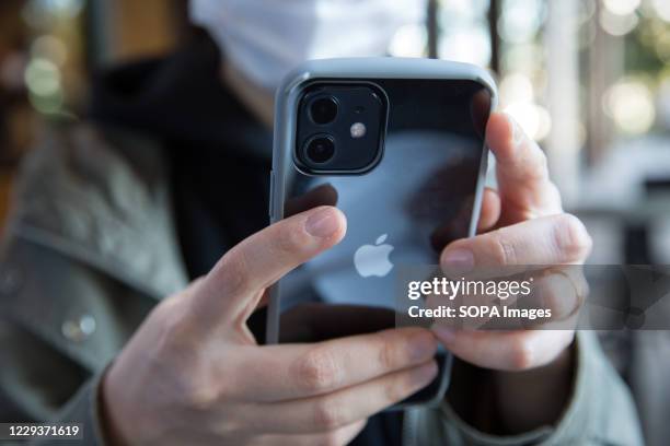 In this photo illustration a woman holds the new iPhone 12 in her hands.