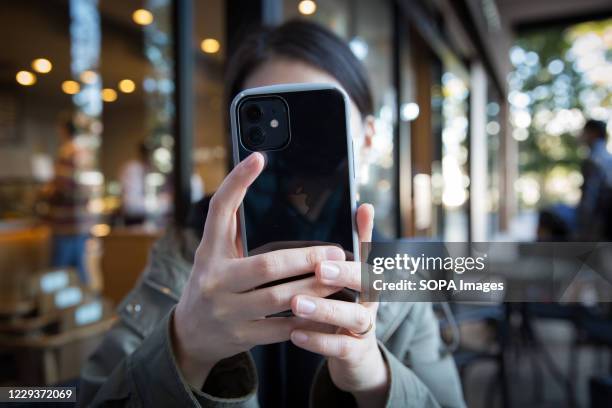 In this photo illustration a woman holds the new iPhone 12 in her hands while taking a picture.