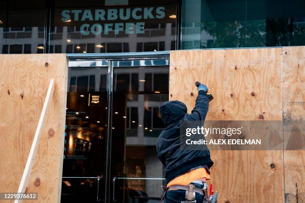 Wooden boards protect a Starbucks location near the White House on October 31, 2020 in Washington, DC. Many Washington businesses are boarding up...