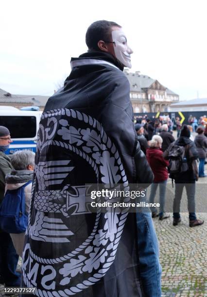 October 2020, Saxony, Dresden: A participant of a demonstration of the movement "Querdenken 351" on the Theaterplatz carries a flag with an imperial...