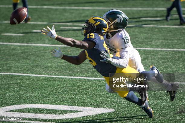 Mike Sainristil of the Michigan Wolverines fails to receive a pass while being covered by Kalon Gervin of the Michigan State Spartans during the...