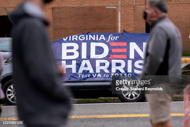 Biden-Harris banner is displayed on a vehicle as voters wait in line to cast their ballots at an early voting center at the Mount Vernon Governmental...