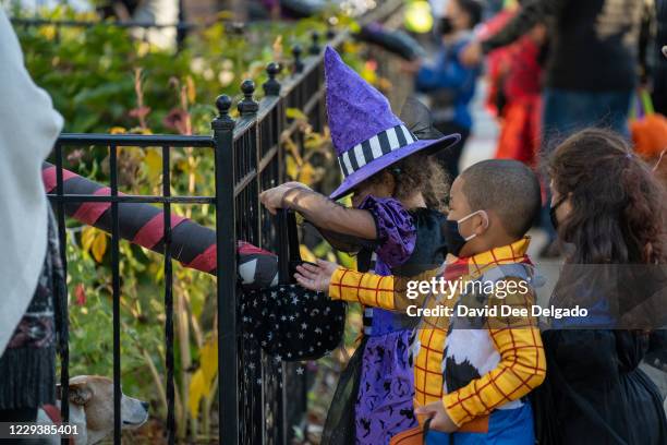 Children receive treats by candy chutes while trick-or-treating for Halloween in Woodlawn Heights on October 31, 2020 in New York City. The CDC...