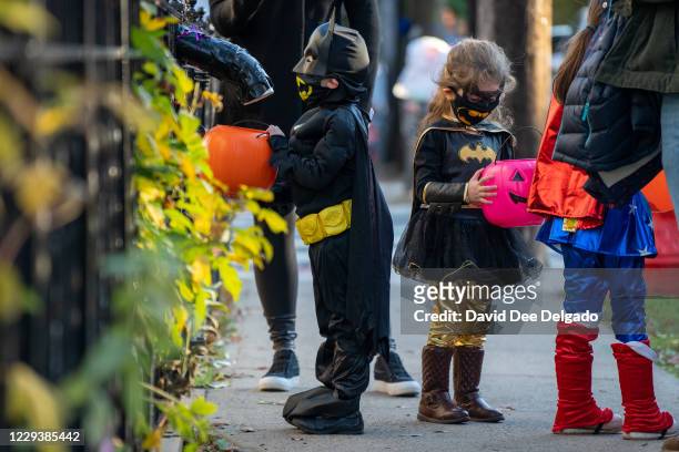 Children receive treats by candy chutes while trick-or-treating for Halloween in Woodlawn Heights on October 31, 2020 in New York City. The CDC...