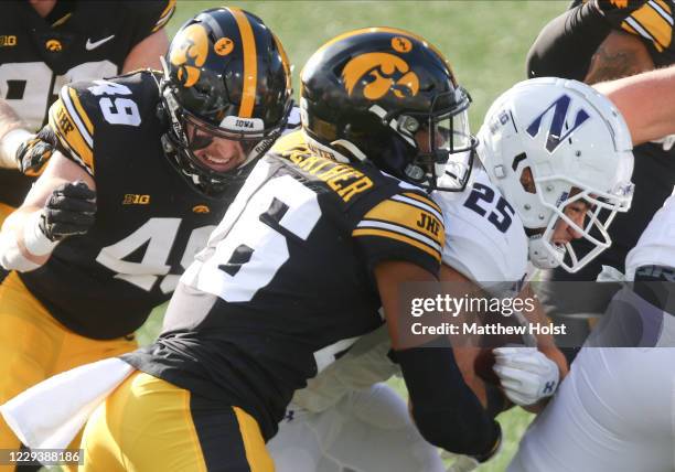 Running back Isaiah Bowser of the Northwestern Wildcats is wrapped up in the first half by safety Kaevon Merriweather and linebacker Nick Niemann of...