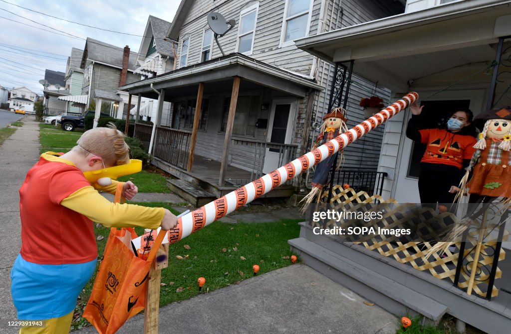 A woman wearing a face mask sends candies down a chute to a...