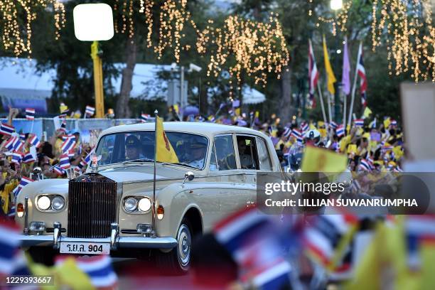 Supporters wave as the the royal limousine carrying Thailand's King Maha Vajiralongkorn and Queen Suthida arrive at the Grand Palace in Bangkok on...