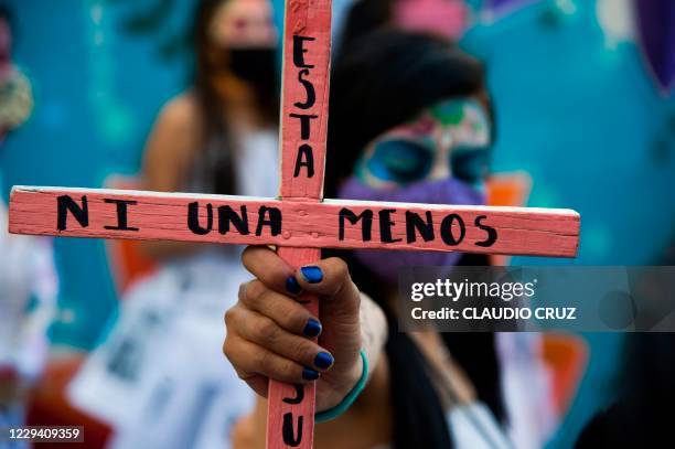 Woman holds a cross reading "Not one less" during "Las Catrinas CDMX 2020" march called by feminist, social and human rights organizations that...
