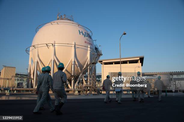 Workers walk by a hydrogen storage tank and loading system at the liquefied hydrogen receiving terminal on Kobe Airport Island in Kobe, Hyogo...