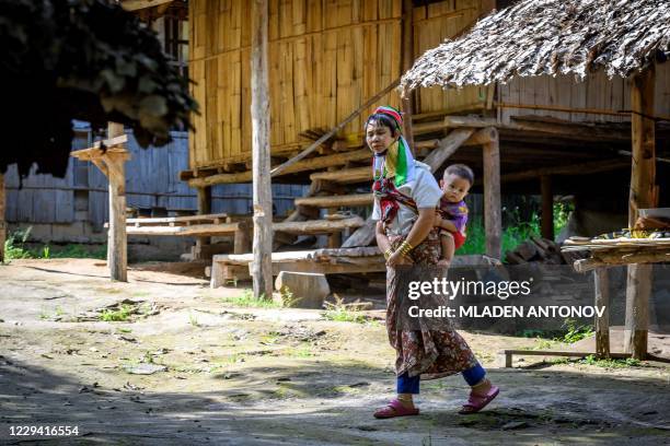 Long Neck Karen woman carries a baby on her back in Baan Tong Luang hill tribes village situated some 30km west of Chiang Mai on November 2, 2020....