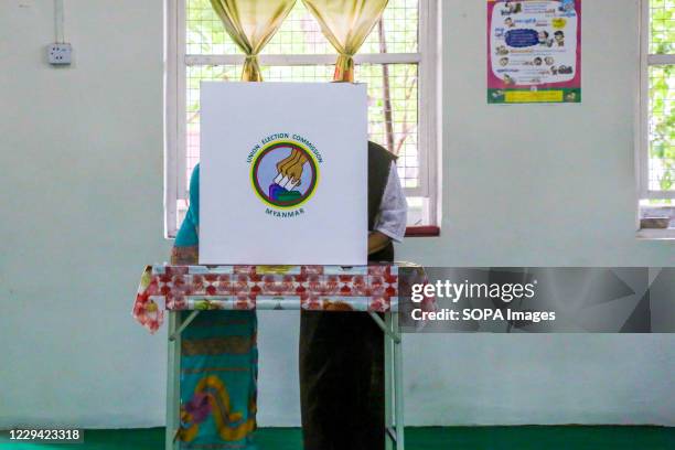 Polling official helps an elderly woman cast her ballot at a Nursing home during the advance voting for elderly in Mandalay. Despite Myanmars growing...