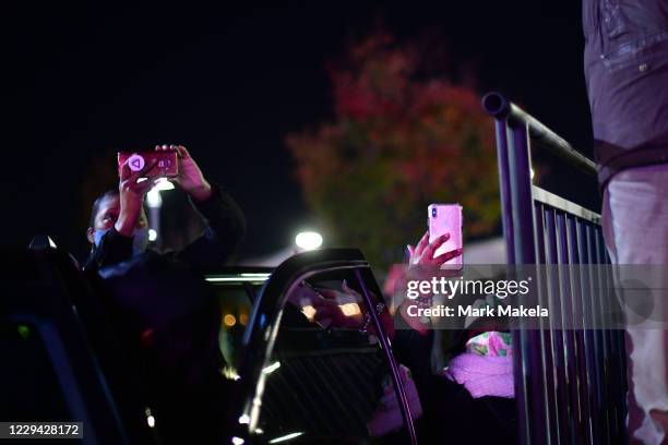 Supporters photograph the stage at a drive-in election eve rally with before Democratic vice presidential nominee Sen. Kamala Harris on November 2,...