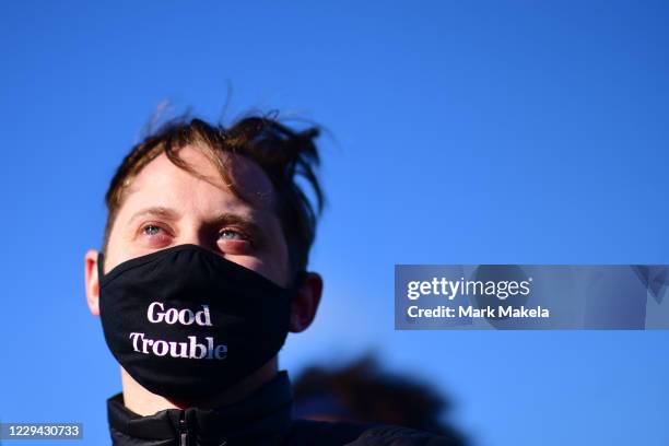 Clay Wild wears a mask that reads "Good Trouble" as Democratic vice presidential nominee Sen. Kamala Harris speaks during a drive-in rally on the eve...