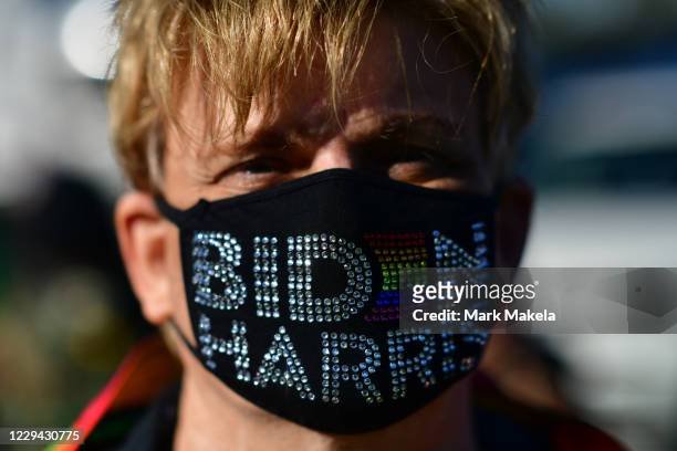 Greg Snyder wears a campaign themed face mask while listening to Sen. Kamala Harris speaks at a drive-in rally on the eve of the general election on...