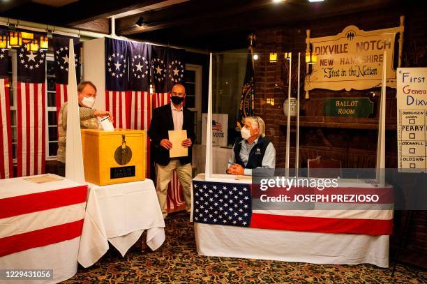 Tom Tillotson drops voters ballots into the ballot box at the Hale House at the historic Balsams Resort during midnight voting as part of the first...