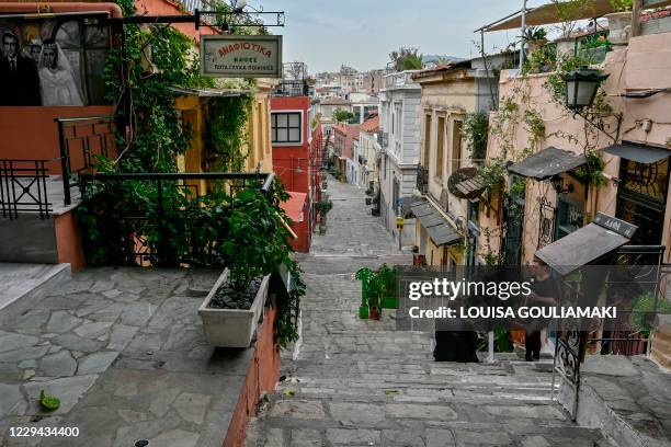 People talk while standing by empty terraces in Plaka district of central Athens as cafes bars and restaurants close due to a partial lockdown to...