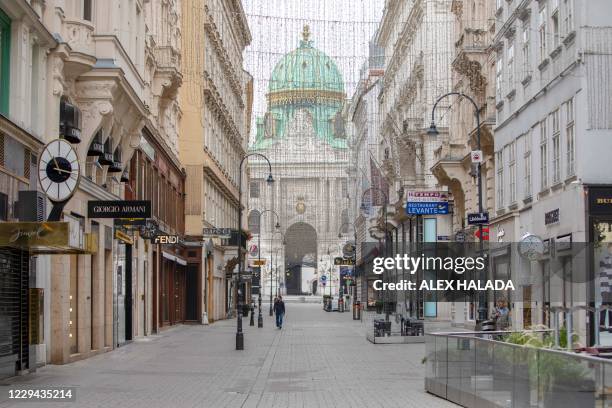 Man walks along the empty street Kohlmarkt among luxury shops closed, as the Michael Dome of the Vienna Hofburg stands in the background, in the...