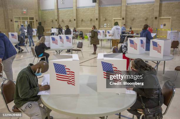 Voters wearing protective masks cast ballots at a polling location for the 2020 Presidential election in Ankeny, Iowa, U.S., on Tuesday, Nov. 3,...