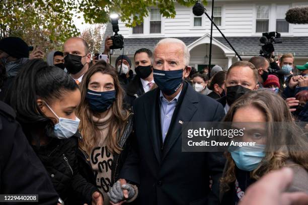 Democratic presidential nominee Joe Biden walks with his granddaughter Natalie Biden as he visits a neighbor's house after stopping at his childhood...