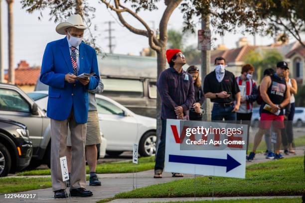 People stand in line to vote as the sun rises at the Main Street Branch Library vote center on November 3, 2020 in Huntington Beach, California....