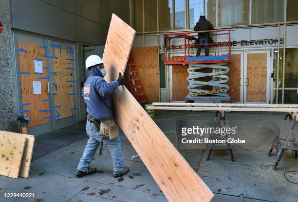 Workers in Downtown Crossing on Arch Street in Boston install 3/4 inch plywood boards over the windows of Marshalls and T.J. Maxx as a precaution on...
