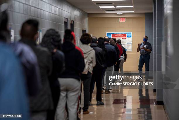 Poll worker talks to a line of voters on election day on November 3, 2020 in Austin, Texas. The United States started voting Tuesday in an election...