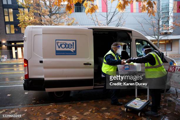 King County Elections drivers Dusty Gepner and Christopher Mugwanya load ballots they collected from a ballot drop box outside the Seattle Community...