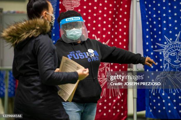 Woman is guided to a polling booth by an election worker wearing a face shield at a polling station in Manchester, New Hampshire, on November 3,...