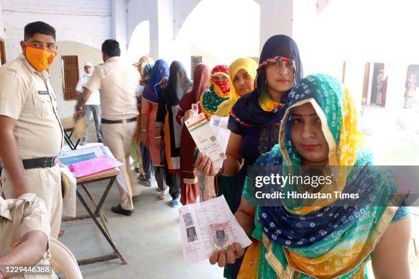 Women voters queue up at a polling station to cast their vote for Baroda By-polls, at Dhanana village on November 3, 2020 in Sonepat, India.