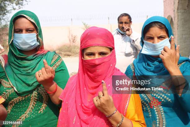 Women voters show their inked fingers at a polling station after casting their vote for Baroda By-polls, at Dhanana village on November 3, 2020 in...
