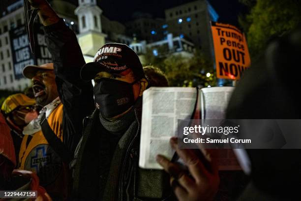 Supporter of President Trump holds up a bible as he is surrounded at Black Lives Matter Plaza in front of the White House on Election Day, November...